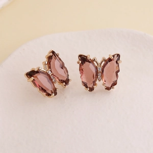 Detailed macro view of butterfly earrings with amber pink resin and gold alloy edges