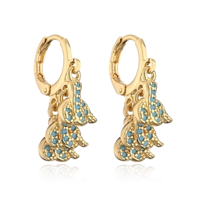 Detalle de pendientes de hoja dorada con piedras turquesas azules y circonitas pequeñas