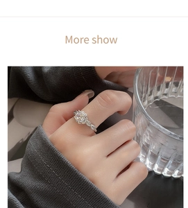 Close-up of twisted silver ring with round zircon worn on finger against knit background