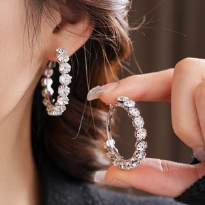 Close-up of oversized silver hoop earrings with sparkling rhinestones on female model
