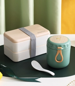 Detail of grey-green insulated soup jar and white bento box with wooden style lid