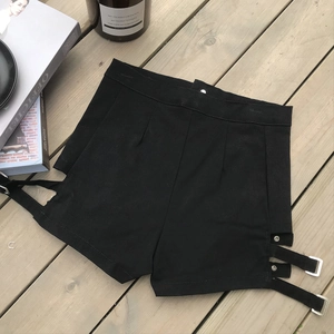 Dettaglio degli shorts neri a vita alta con ritagli laterali e cinturini con fibbia argento
