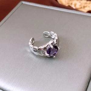 Detail of silver open ring featuring a purple round gemstone and heart-shaped band