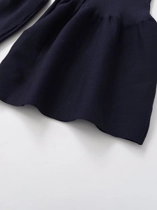 Detailed close-up of dark blue knit fabric with ribbed cuff and wavy textured hemline