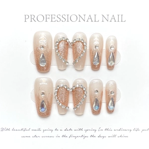Détails d'ongles faits main nude avec dégradé pailleté et motif cœur en strass