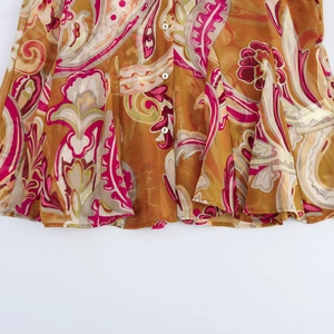 Detail view of paisley chiffon shirt with delicate pleats and gold-pink vintage pattern