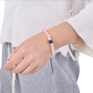 Detail of pink crystal beaded bracelet with a black lava stone on a female wrist