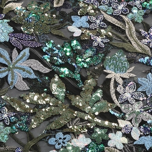 Macro detail of intricate blue and gold floral sequins on luxury black mesh fabric