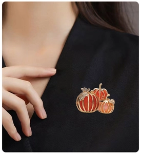Detail of pumpkin brooch on black lapel showing sparkling rhinestones and gold alloy frame
