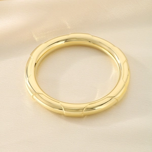 Macro view of polished gold geometric hollow bangle on champagne satin fabric background