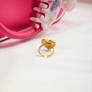 Detail of a gold-plated heart-shaped open ring with light inlay on a soft fabric backdrop