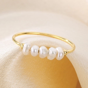 Elegante anello in acciaio al titanio dorato con cinque perle naturali su sfondo di seta
