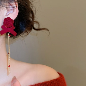 Detail of red velvet rose bow earrings with long gold tassel and crystal accents