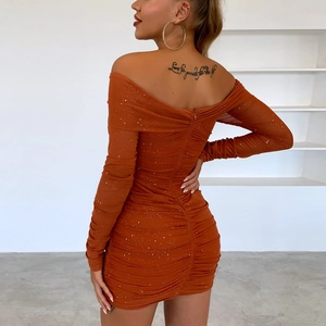 Détail d'une robe moulante pailletée marron-orange à épaules dénudées avec texture froncée