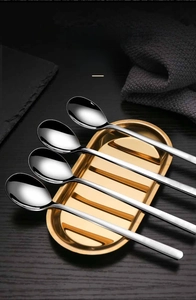 Mirror-polished stainless steel long-handle spoons displayed on a gold metal tray
