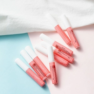 Flat lay macro view of multiple pink tubes of professional nail glue with white caps
