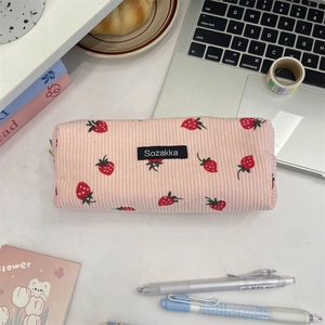 Pink corduroy pencil case with red strawberry print and zipper on office desk