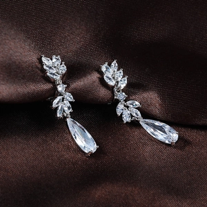 Macro detail of elegant long drop earrings featuring sparkling pear-shaped zircons on silk