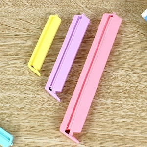 Set of 12 colorful plastic snack sealing clips in 3 sizes on wooden background