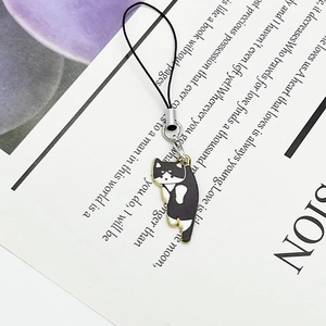 Detailed view of cartoon cat charm with gold trim and black lanyards on paper background