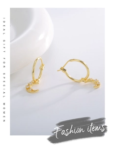 Detail of gold hollow moon drop earrings with zircon inlay on white ceramic tray