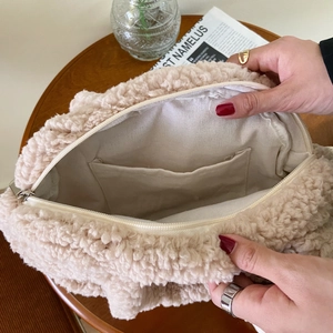 Detail view of the beige fuzzy handbag showing interior lining, pocket and zipper closure