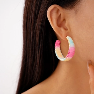 Close-up of pastel woven C-shape hoop earrings showing macaron gradient textures