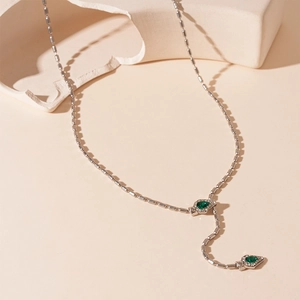 Détail du collier serpent argenté avec gemmes vert émeraude et accents de zircon