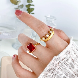 Detail of red square zircon ring and gold band set worn on hand with cozy sweater