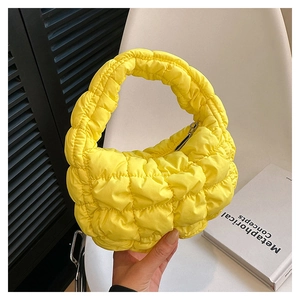 Macro view of bright yellow quilted cloud bag showing pleated puff fabric texture