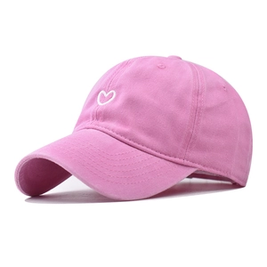 Detail of pink cotton baseball cap with white heart embroidery and curved brim