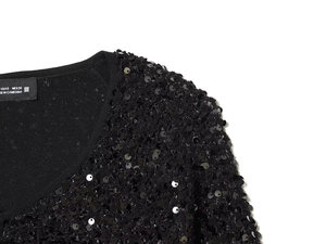 Detailed close-up showing black sequins texture and collar tag on the sequin jacket