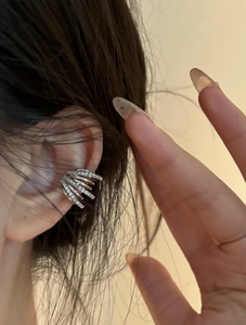 Close-up of multi-layer silver ear cuff with zircon inlay on a female ear