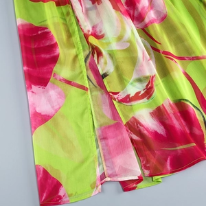 Gros plan sur le tissu mousseline à fleurs roses et vertes avec détail de fente latérale