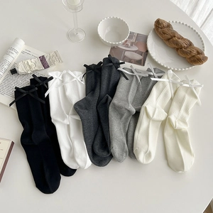 Flat lay of colorful knit mid-calf socks with bow details and cozy lifestyle items