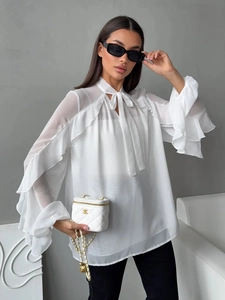 Detailed view of white chiffon blouse with layered ruffle cuffs and neck bow tie