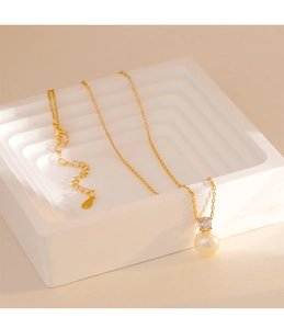 Detail of gold snake chain necklace featuring a round pearl pendant and zircon accent