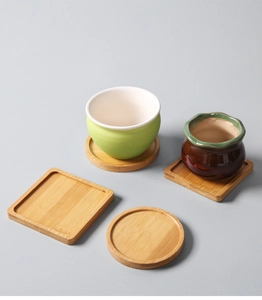 Close-up of ceramic pots and natural bamboo drainage trays in round and square shapes