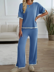 Detail of blue knitted set with yellow striped cuffs on top and wide-leg trousers