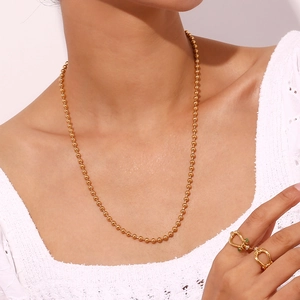 Detail showing gold 4mm bead chain necklace and minimalist twisted ring on a female model