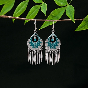 Detail of vintage silver boho earrings with blue enamel drops and metal tassels on wood