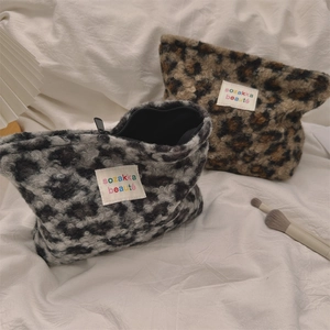 Close-up of plush leopard print makeup bag featuring a white brand label and black zipper