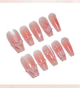 Close-up detail of pink blush press-on nails featuring 3D butterflies and pearl accents
