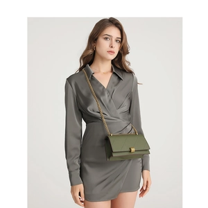 Olive green quilted crossbody bag with gold chain strap shown on model in grey dress