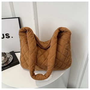Brown corduroy tote bag with diamond quilting and soft straps on a minimalist table