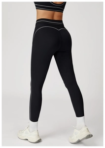 Detail view of high-waist black yoga leggings with V-shaped white stitching on back