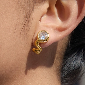 Gold snake earrings with round zircon stones shown on ear for a luxury style