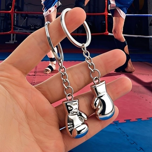 3D silver metal boxing glove keychain pair shown against a boxing ring background