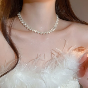 Close-up of elegant double-layered pearl necklace worn with a feather evening dress
