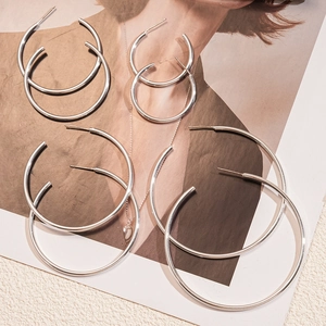 Polished silver hoop earrings in four sizes displayed on a fashion magazine background
